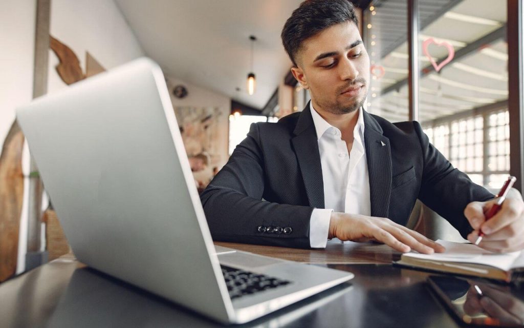 Man with laptop and notepad and pen