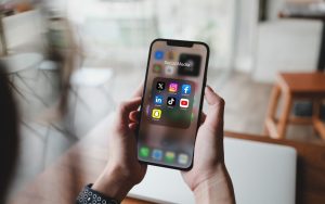 Hand holding a smart phone with social media app icons on the screen